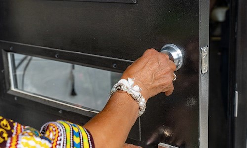 A resident inserting their house key into the front door