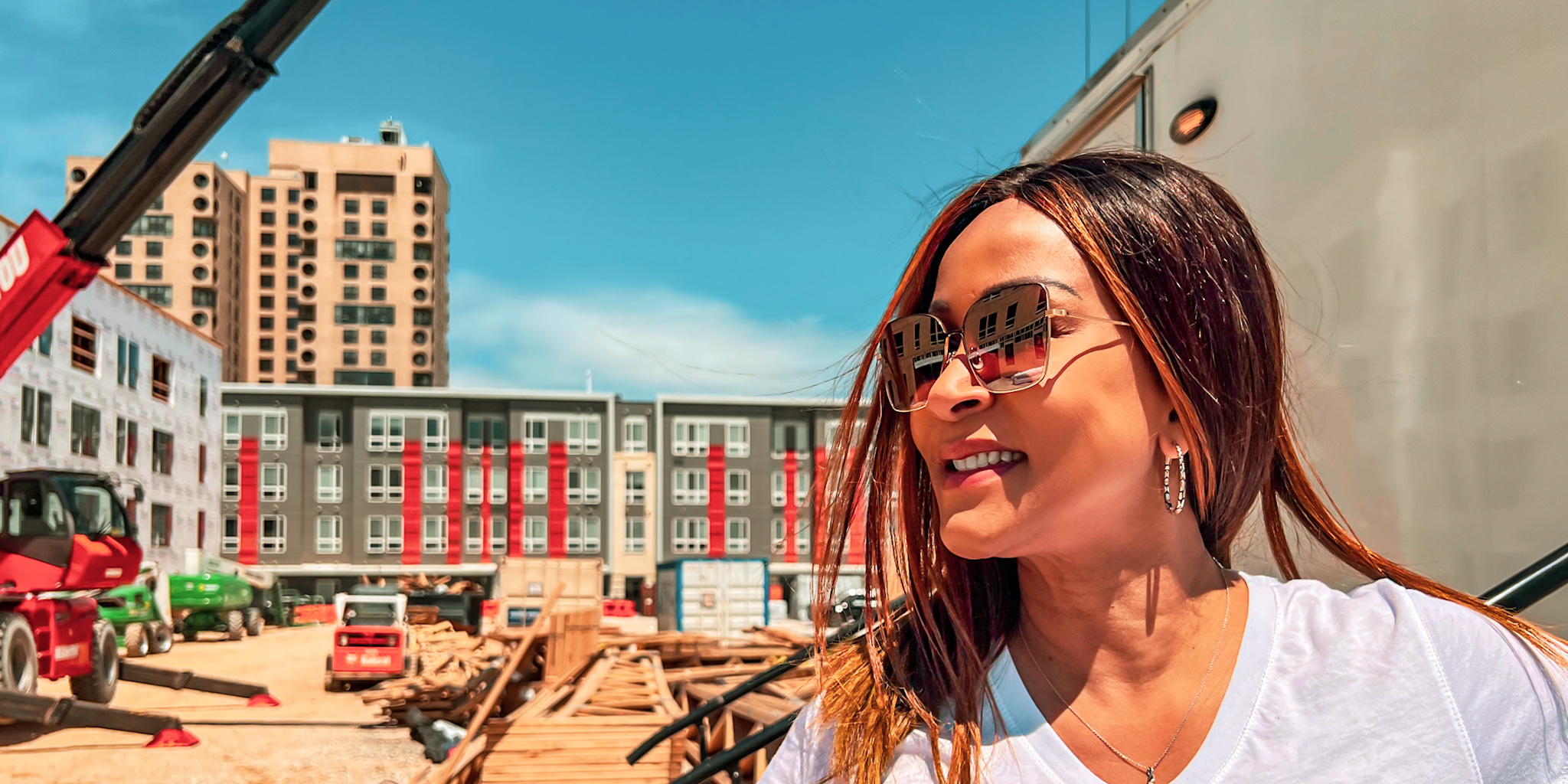 Janet Abraham posing on the Somerset 2 construction site grounds in front of a large crane